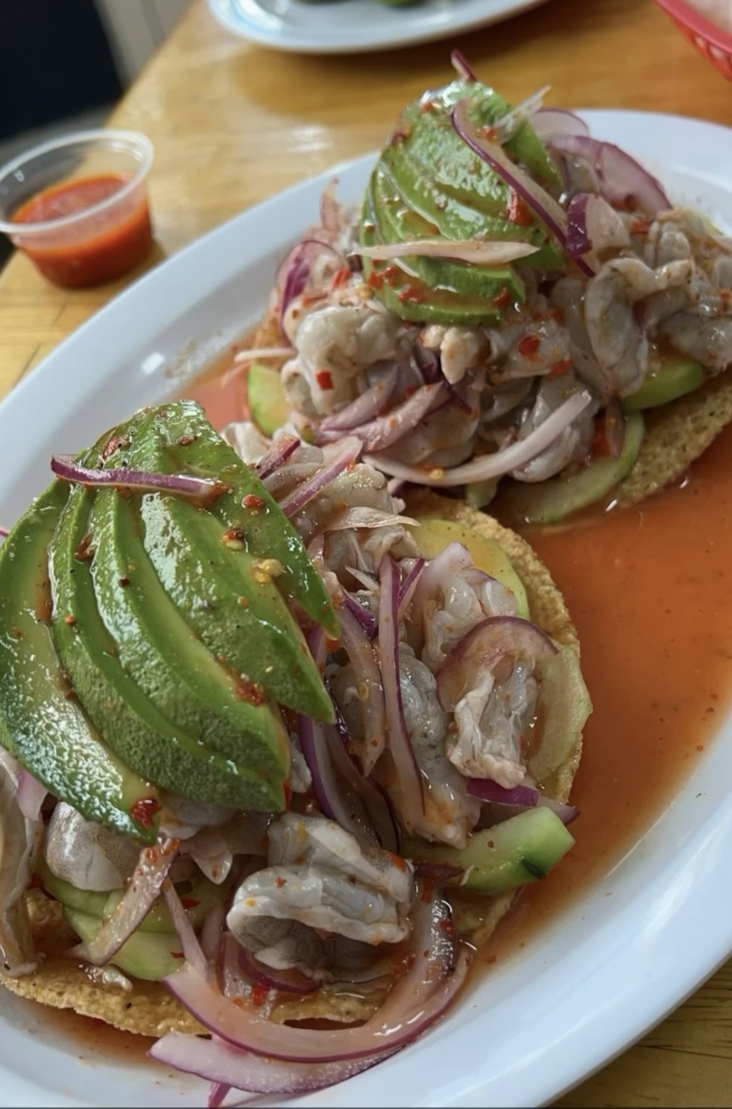 Tostadas de camarón topped with sliced avocado, red onion and salsa
